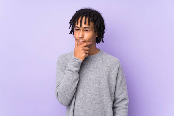 Joven afroamericano aislado sobre fondo púrpura que tiene dudas y con expresión de cara confusa - Foto, Imagen