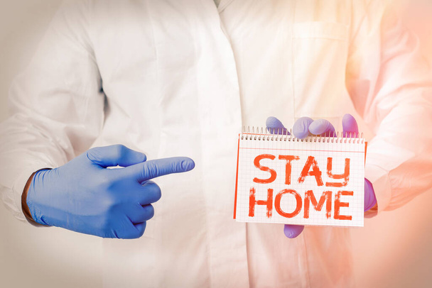 Writing note showing Stay Home. Business photo showcasing not go out for an activity and stay inside the house or home Laboratory Technician Featuring Sticker Paper Smartphone. - Photo, Image