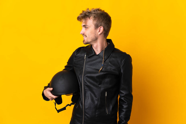 Man with a motorcycle helmet isolated on yellow background looking side - Foto, imagen