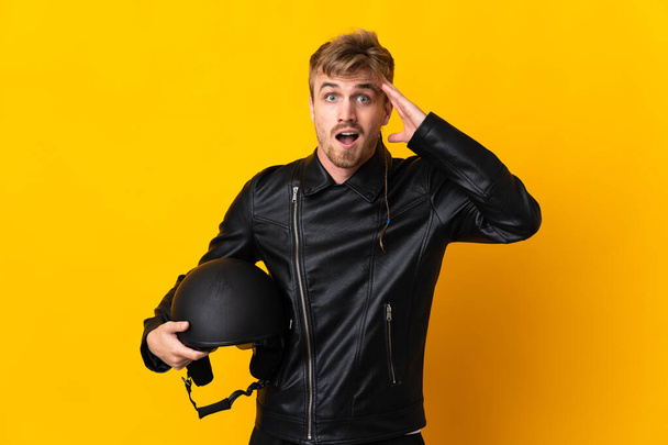 Uomo con casco moto isolato su sfondo giallo con espressione a sorpresa - Foto, immagini