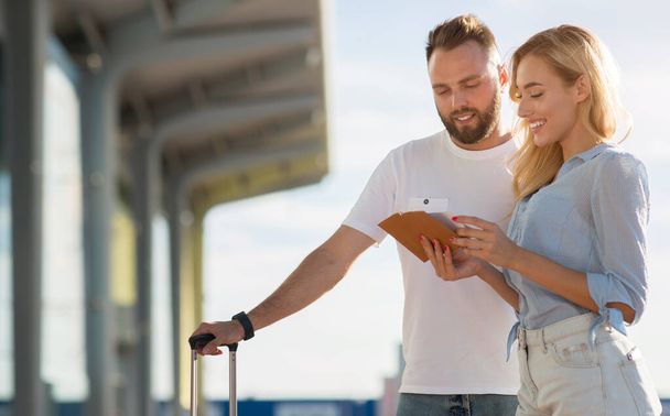 Travel concept. Lovely couple checking tickets outside - Photo, Image