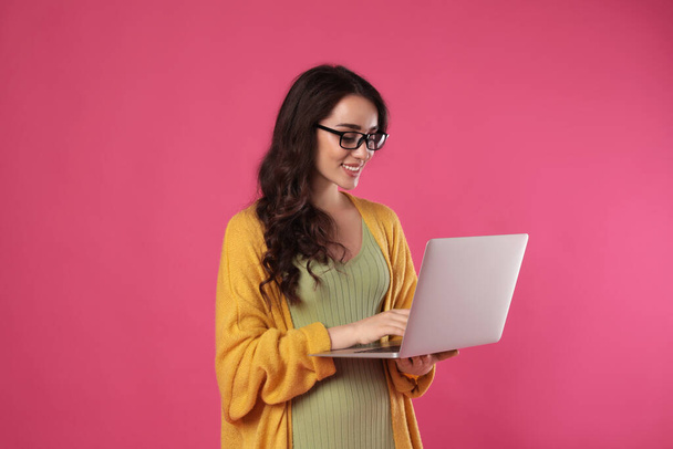 Young woman with laptop on pink background - Fotografie, Obrázek