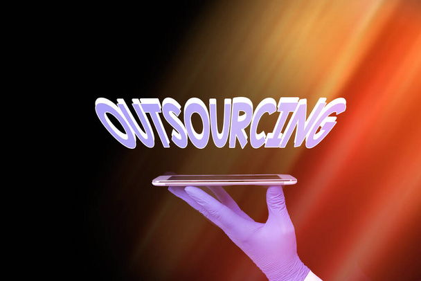Writing note showing Outsourcing. Business photo showcasing obtain goods or a service from an outside or foreign supplier Displaying Sticker Paper Accessories With Medical Gloves On. - Photo, Image