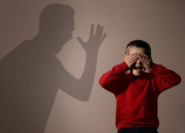 Child abuse. Father yelling at his son. Shadow of man on wall - Foto, afbeelding