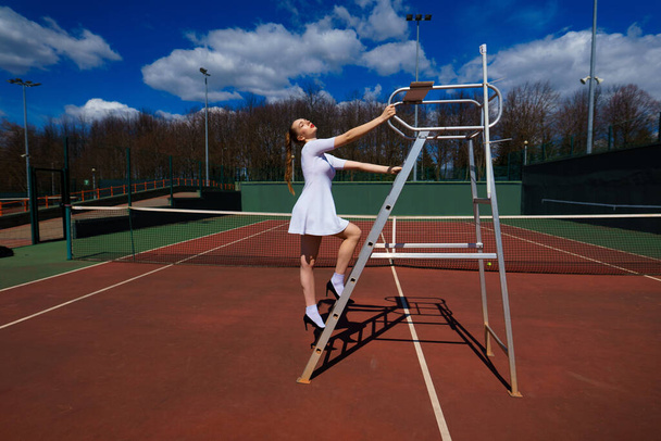 Mulher sensual com raquete de tênis na rede no gramado. Actividade, energia, energia. Desporto, treino, treino. Bem-estar, saúde do corpo
 - Foto, Imagem