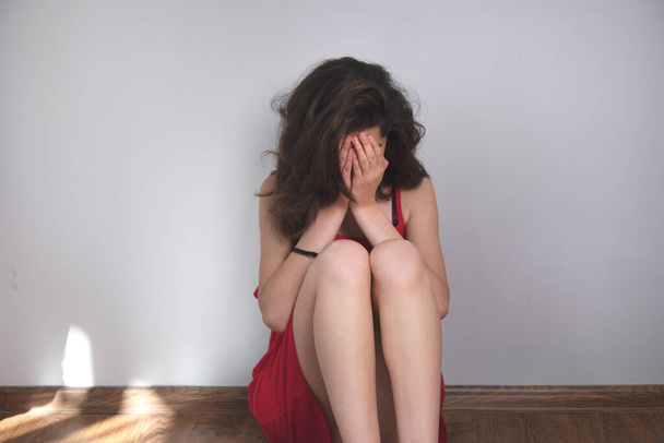 λυπημένη νεαρή γυναίκα που κάθεται στο πάτωμα - Φωτογραφία, εικόνα