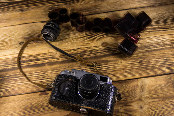 Ρετρό φωτογραφική μηχανή με φωτογραφικό φιλμ και φακό σε ξύλινο τραπέζι - Φωτογραφία, εικόνα