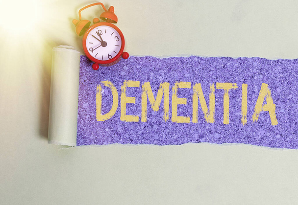Handwriting text writing Dementia. Concept meaning usually, a progressive condition marked by multiple deficits Rolled ripped torn cardboard placed above a wooden classic table backdrop. - Photo, Image