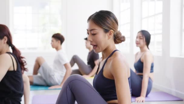 Young Asian sporty attractive people practicing yoga lesson with instructor. Asia group of women exercising healthy lifestyle in fitness studio. Sport activity, gymnastics or ballet dancing class. - Footage, Video