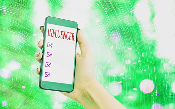 Handwriting text writing Influencer. Concept meaning the an individual who inspires or guides the actions of others Modern gadgets with white display screen under colorful bokeh background. - Photo, Image