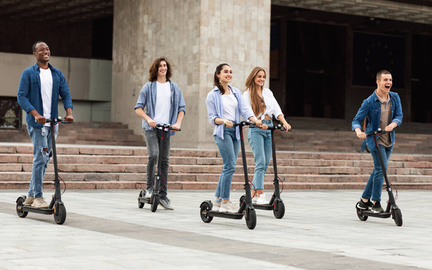 Five friends having pleasant ride on motorized kick scooters - Photo, Image