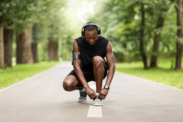 Černý sportovec vázání tkaničky na park jogging stezka - Fotografie, Obrázek