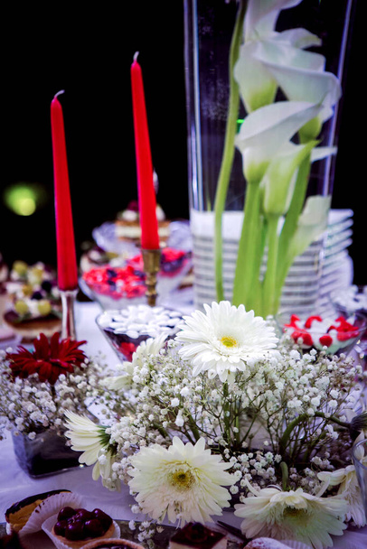červené svíčky v kovovém svícnu a červené a bílé květy, svatební výzdoba, sloužící pro speciální akci, na čerstvém vzduchu, pod širým nebem - Fotografie, Obrázek