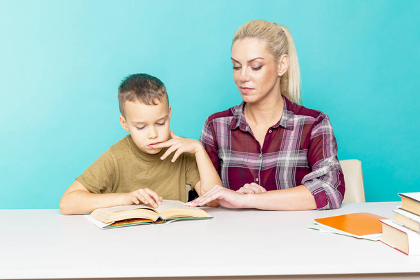 Mutter hilft ihrem Sohn bei den Hausaufgaben vor isoliertem rosa Hintergrund. Distanzierte Bildung - Foto, Bild