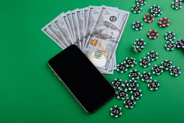 携帯電話カジノオンライン。緑のゲームテーブル上のチップと携帯電話やゲームカード。ギャンブル中毒ゲーム割れ。ポーカーオンライン - 写真・画像