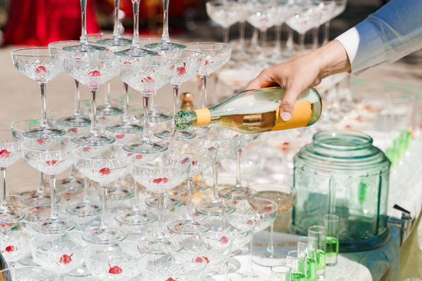 Číšník nalije šampaňské do křišťálových sklenic. Šumivé víno nalévající se ve sklenici vína v letní den. Catering pro podnikatele - Fotografie, Obrázek