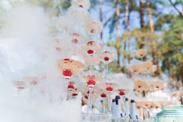 Piramida szampana z dymem z suchego lodu i musującego wina i czerwonej wiśni w środku. catering dla ceremonii ślubnej i ludzi biznesu - Zdjęcie, obraz