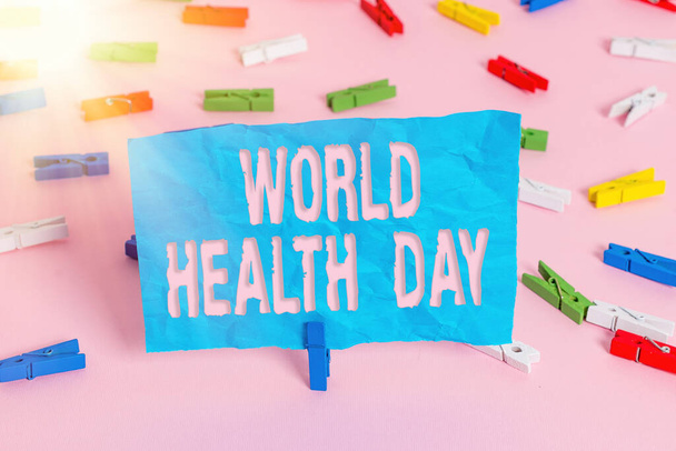 Dünya Sağlık Günü 'nü gösteren kavramsal el yazısı. Küresel Sağlık Bilinci Günü 'nü gösteren iş fotoğrafı her yıl 7 Nisan' da kutlandı. Renkli çamaşır iğnesi kağıtları boş pembe zemin ofisini hatırlatıyor.. - Fotoğraf, Görsel