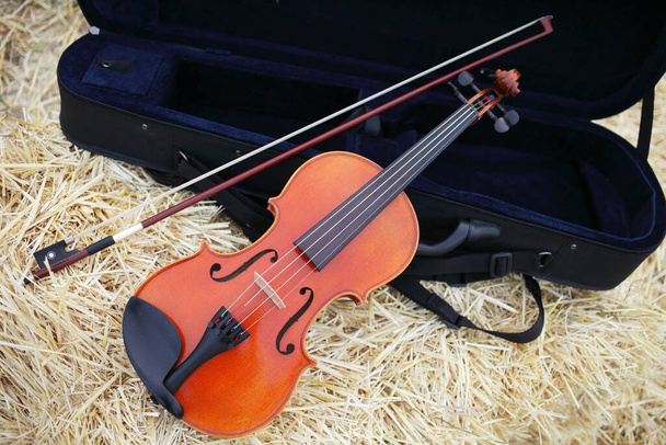 Um violino e arco colocados em uma pilha de palha no campo. Treino de violino musical. Fiddlestick, a actuar. Conceito, barroco. Musical, violino
. - Foto, Imagem