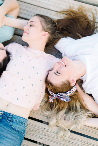  beautiful girls lie on a wooden pier and holding hands. rest, picnic. - Fotoğraf, Görsel