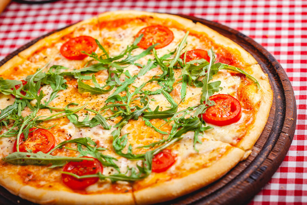 Pizza Margherita (Margarita) con rúcula fresca sobre tabla de madera. De cerca.
 - Foto, Imagen