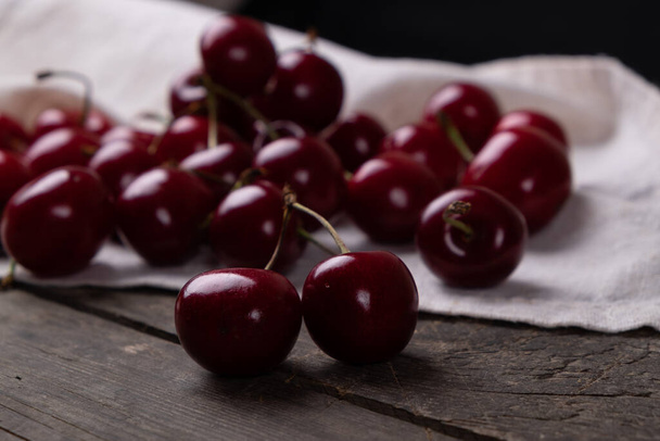 A scattering of red cherries from dishes on a wooden table, macro - Photo, Image