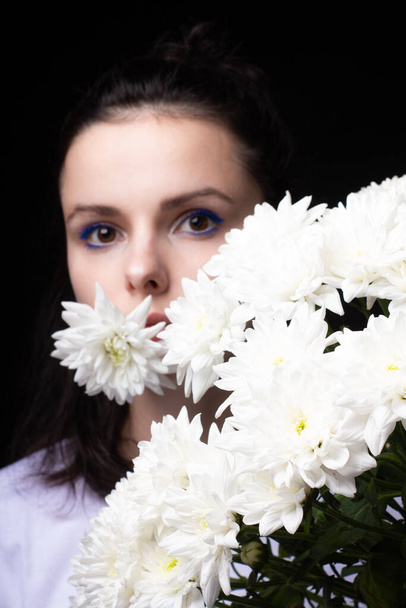 woman with a bouquet of chrysanthemums on a black background - Foto, imagen
