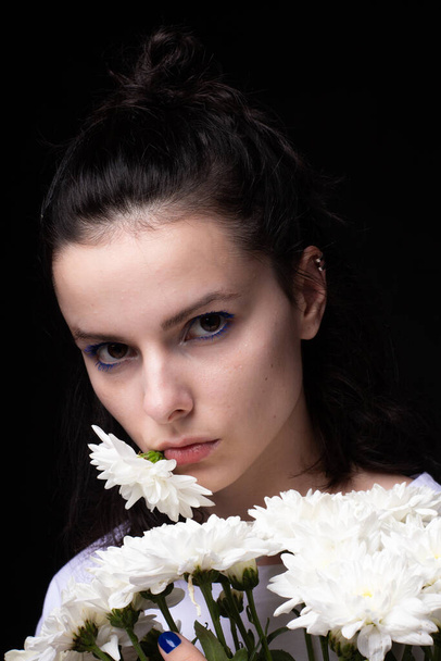 woman with a bouquet of chrysanthemums on a black background - Foto, afbeelding