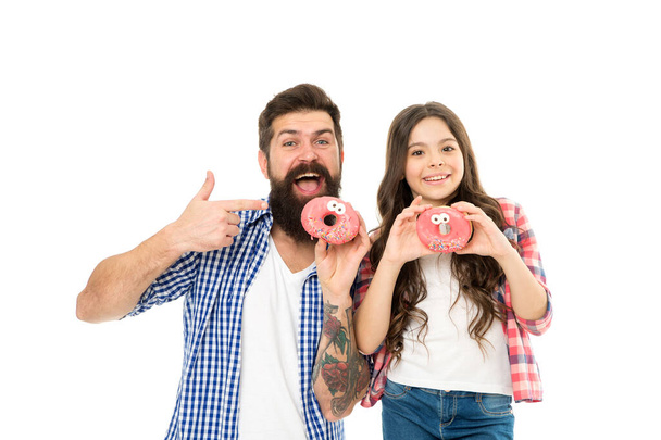 Sweets and treats concept. Daughter and father eat sweet donuts. Happiness and joy. Hungry kid. Bakery shop. Fathers day. Sweet tooth. Girl child and dad hold glazed donuts. Cheerful family - Foto, immagini