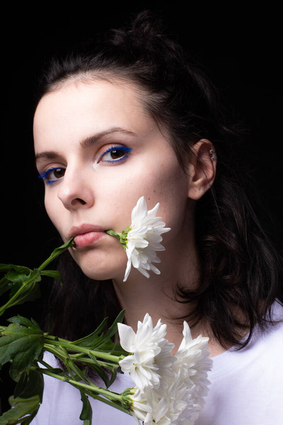 woman eating white flowers on black background - Foto, afbeelding