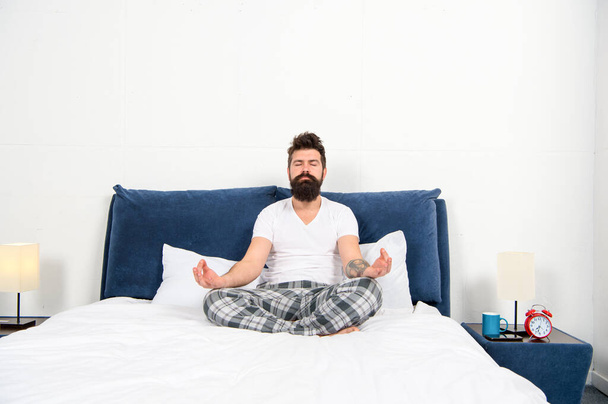 Hombre pijama sentarse cama dormitorio mañana meditación, calmar concepto
 - Foto, Imagen