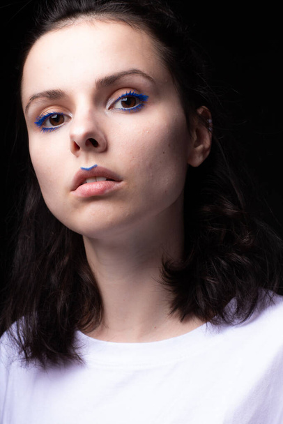 fashionable woman with blue eye makeup and check mark on lips, portrait close-up, black background - Valokuva, kuva