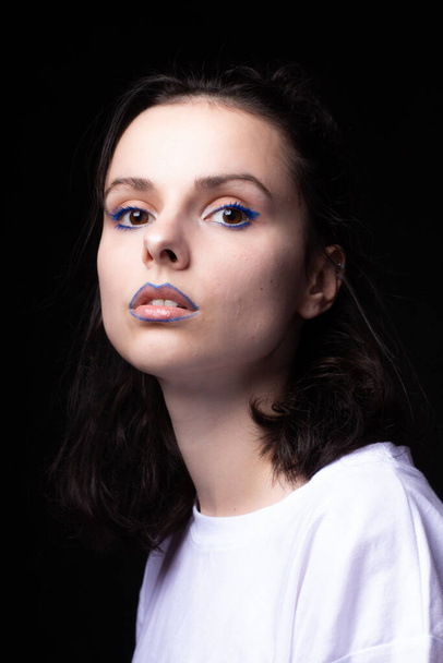 mujer de moda con maquillaje de ojos azules y marca de verificación en los labios, retrato de primer plano, fondo negro
 - Foto, imagen