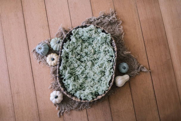 Newborn digital background - natural oval woven bowl with green fluffy faux fur layer, jute and colorful pumpkins on wooden background, Newborn Thanksgiving background - Photo, Image