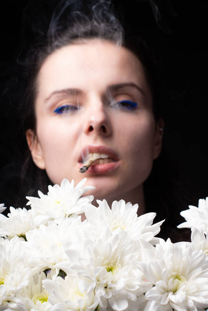 Женщина с букетом белых хризантем курит сигарету - Фото, изображение