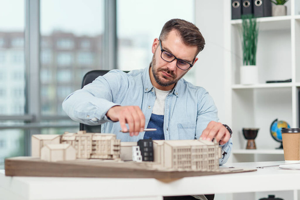 Handsome architect at glasses working on a construction project and examines project of a residential complex on which he works. - Photo, image