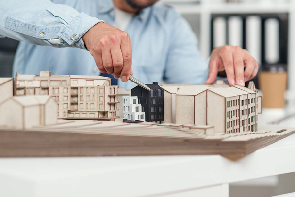 Close up architects hands constructing model of buildings and examines his work. Urban architecture and design concept. - Valokuva, kuva