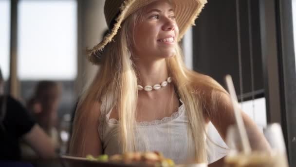 Female with Long Blonde Sitting in Cafe Looking Sideways Smiling - Materiał filmowy, wideo