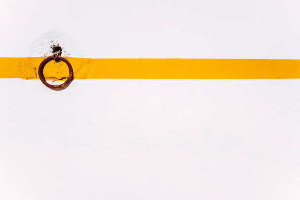 Rural background of a rusty ring on a white wall with orange line to tie animals. - Photo, Image