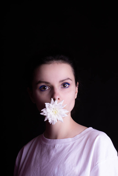 beautiful girl with chrysanthemum in her mouth, dark background - Valokuva, kuva