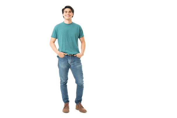 Souriant beau jeune homme debout avec les mains dans des poches de jeans en denim - Photo, image