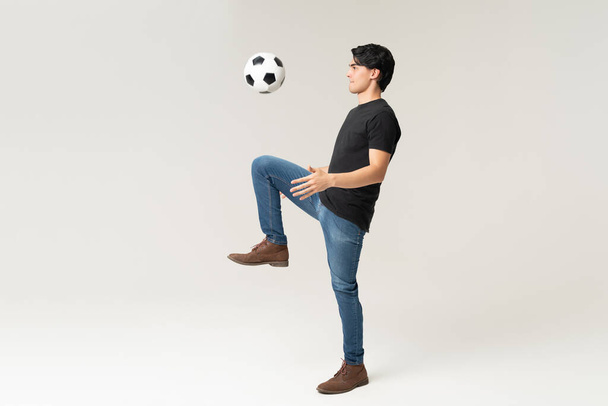 Täyspitkä komea nuori mies rento pelaa jalkapalloa studiossa - Valokuva, kuva