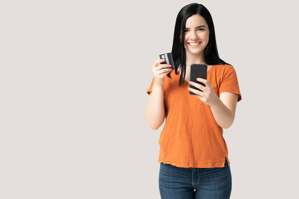 Cep telefonu kullanırken elinde kredi kartı tutan gülümseyen beyaz kadın portresi - Fotoğraf, Görsel