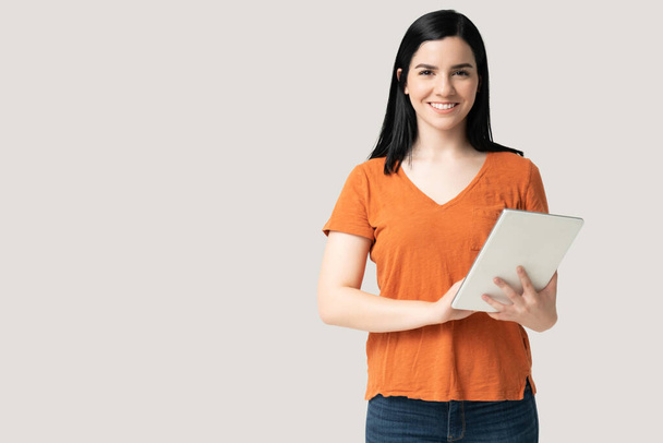 Sorridente attraente giovane donna utilizzando tablet digitale mentre in piedi in casuals - Foto, immagini