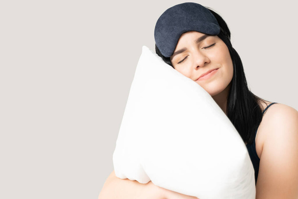 Aantrekkelijke blanke jonge vrouw omarmen kussen en glimlachen tijdens het slapen - Foto, afbeelding