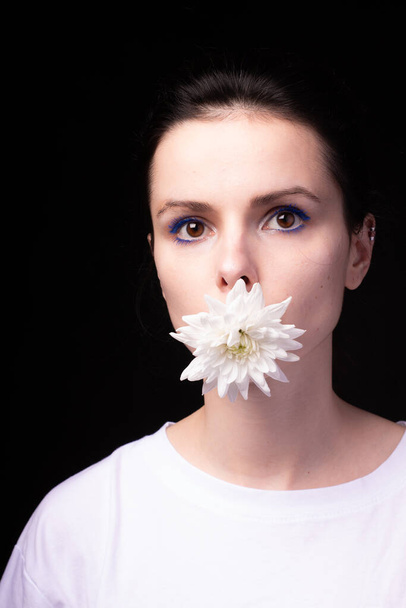 woman holding a white chrysanthemum in her mouth, black background - Foto, Imagem