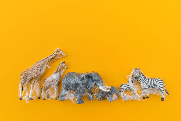 Animals is entangled in a plastic bag. Plastic animal concept. Yellow background. Environmental pollution problem. Flat lay Copy space - Фото, изображение