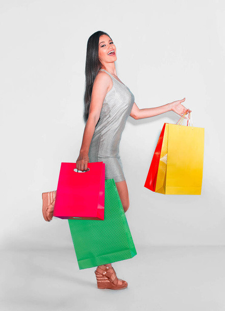 Mulher expressiva andando compras com sacos coloridos em um fundo branco isolado - Foto, Imagem