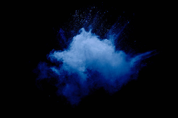 Niebieski proszek eksploduje chmurą na czarnym tle.Uruchomione niebieskie cząsteczki pyłu splash na tle. - Zdjęcie, obraz