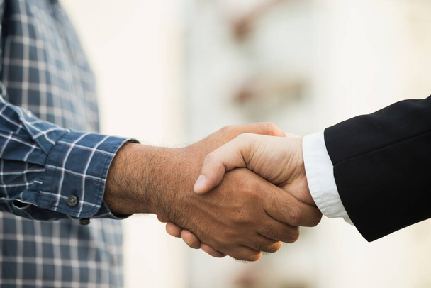 Dois homens a apertar a mão ao negócio do acordo de sucesso. Empresários vestindo camisa scott na cidade vista de fundo. - Foto, Imagem